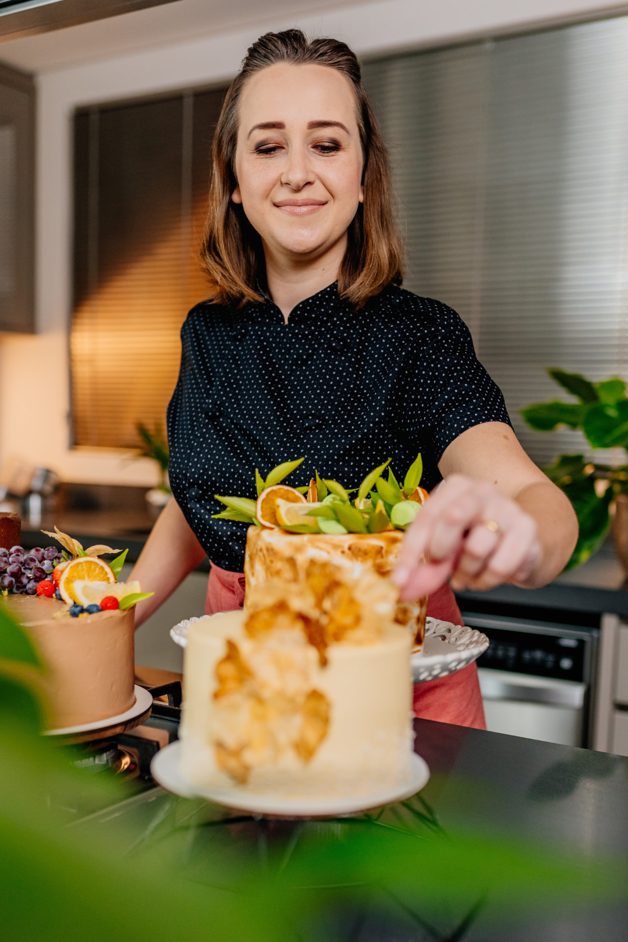 Chef Patrícia Brüske decorando bolo com frutas em sua cozinha